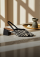 Black and white patterned sandal on a light surface with a soft background