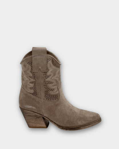 Brown cowboy boot with decorative cut-out design on a light gray background