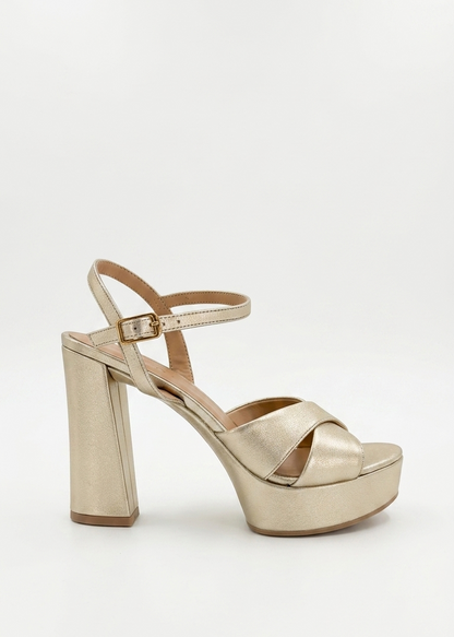 A metallic gold platform sandal with a block heel, open toe, and ankle strap, shown from a side profile on a light gray background.